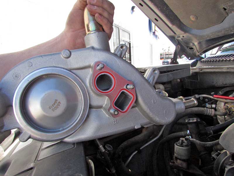 The old water pump gets tossed and the new water pump gets prepped for installation with fresh gaskets.